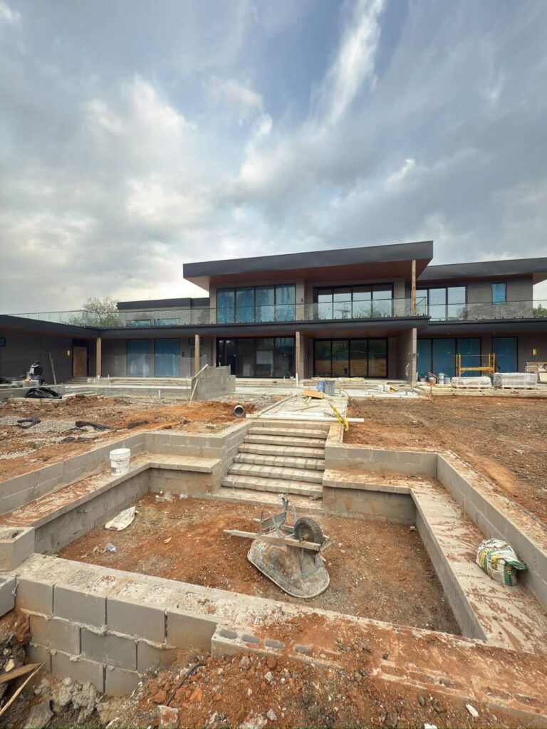 Custom pool mid-construction behind a modern two-story home, before decking and plaster
