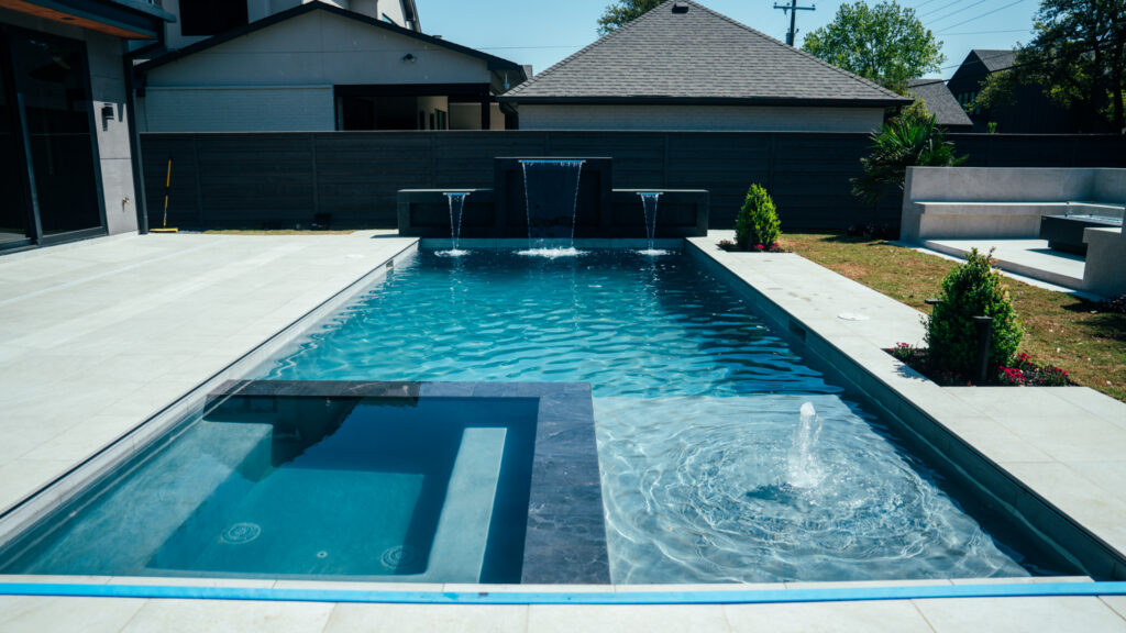 Rectangular pool with raised spa, tanning ledge and sheer descents on a sunny day