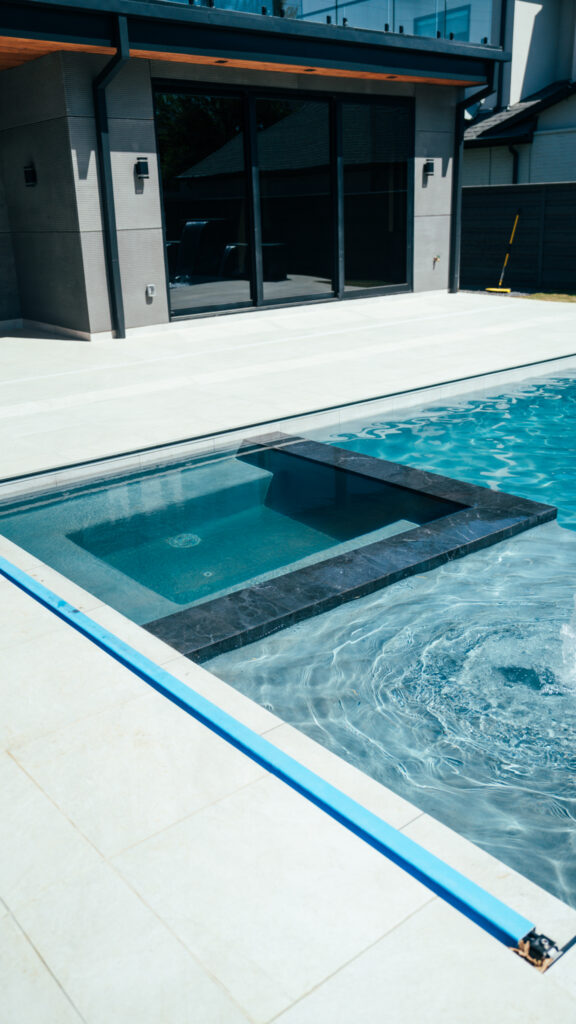 Close-up of a tanning ledge and dark tile coping on a custom gunite pool