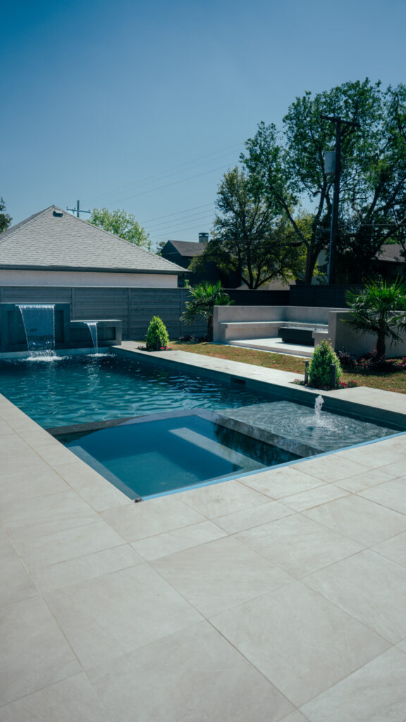 Custom pool with three sheer descent waterfalls and a raised spa in a modern North Texas backyard