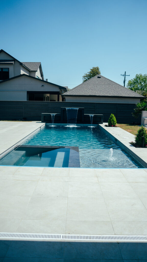 Geometric gunite pool with sheer descent water features, tanning ledge and bubblers, built by Blue Wave Outdoor Living