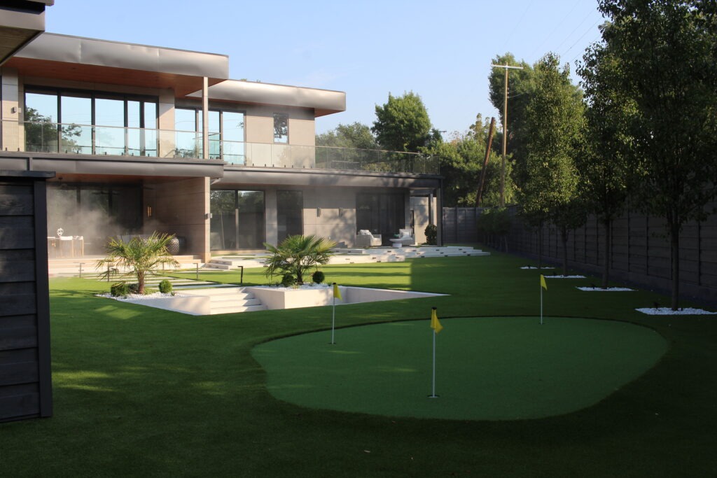 Backyard putting green with artificial turf beside a modern home